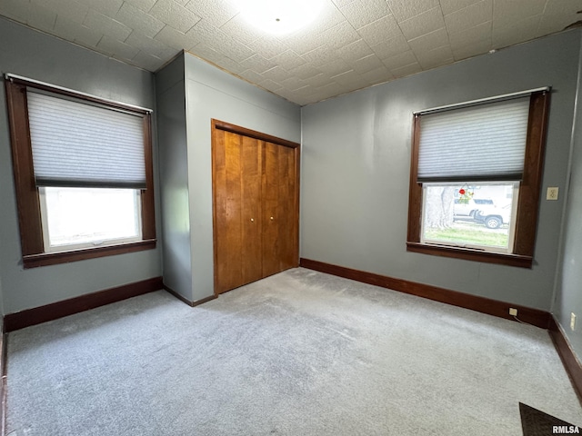 unfurnished bedroom featuring carpet flooring, baseboards, and a closet