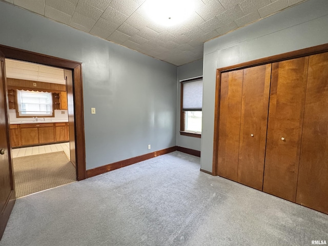 unfurnished bedroom featuring a closet, multiple windows, carpet flooring, and a sink