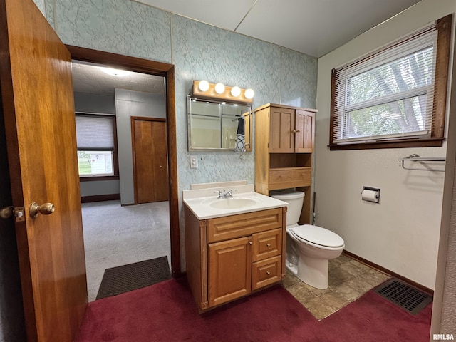 bathroom with vanity, a wealth of natural light, toilet, and visible vents