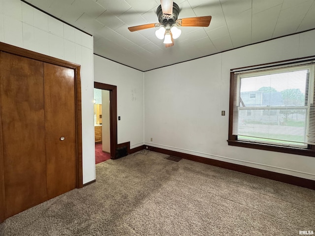 unfurnished bedroom featuring carpet flooring, baseboards, visible vents, and ceiling fan