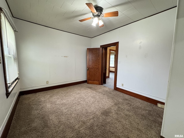 carpeted spare room with ceiling fan and baseboards