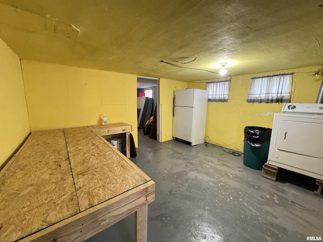 below grade area featuring freestanding refrigerator and washer / clothes dryer