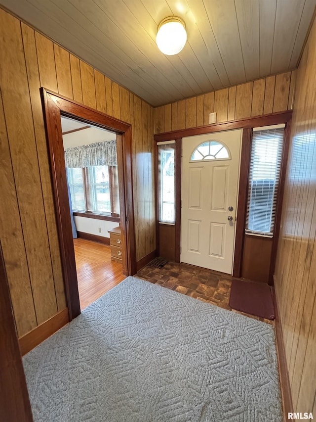 entryway featuring baseboards, wooden walls, wooden ceiling, and dark wood-style floors