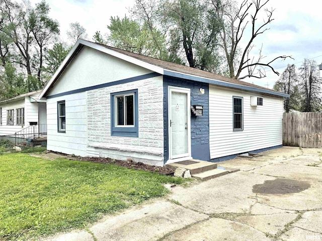 view of front of house with fence, stone siding, and a front lawn