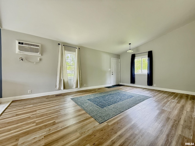 interior space featuring baseboards, a wall mounted AC, and wood finished floors