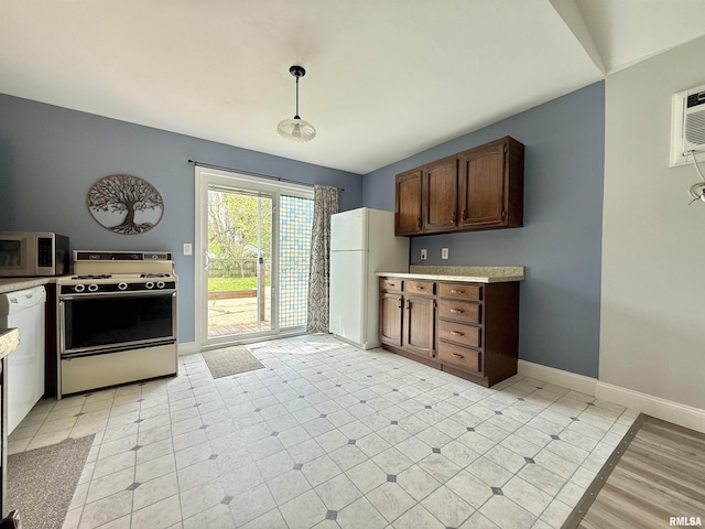 kitchen featuring range with electric cooktop, light countertops, baseboards, stainless steel microwave, and freestanding refrigerator