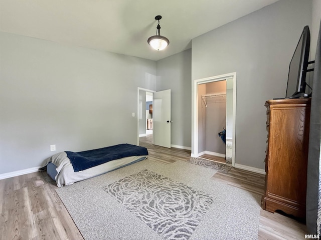 bedroom with baseboards, wood finished floors, and a closet