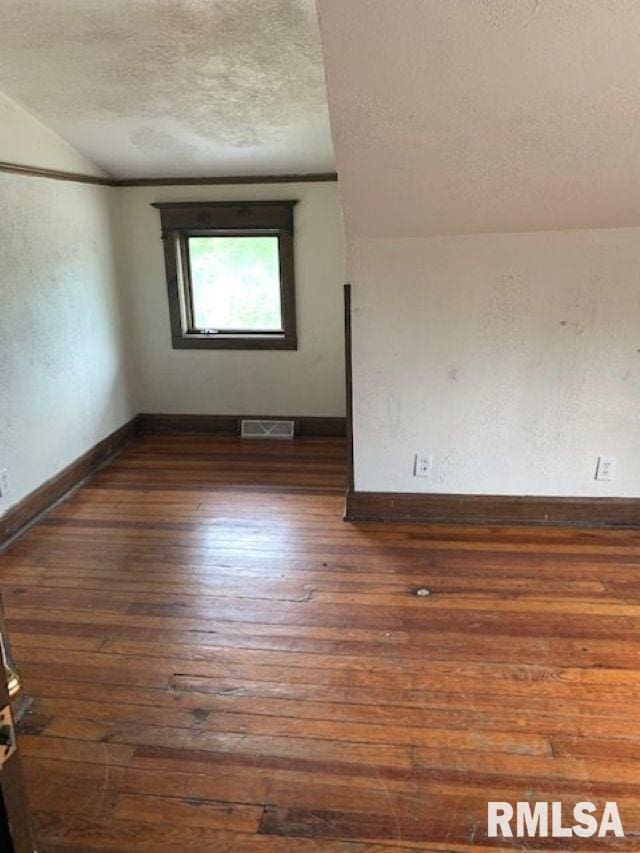 400-402 E Laurel, Springfield, IL 62704 - empty room with a textured ceiling, vaulted ceiling, hardwood / wood-style floors, and baseboards