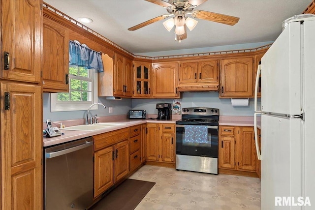 3300 Winch Rd, Springfield, IL 62707 - kitchen with appliances with stainless steel finishes, a sink, brown cabinets, light countertops, and under cabinet range hood