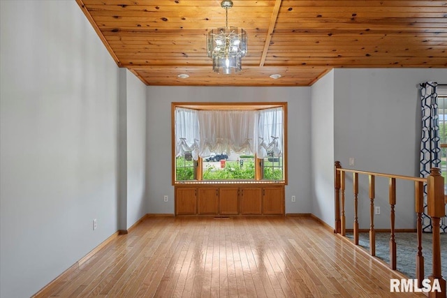 spare room featuring baseboards, light wood finished floors, a notable chandelier, and wooden ceiling