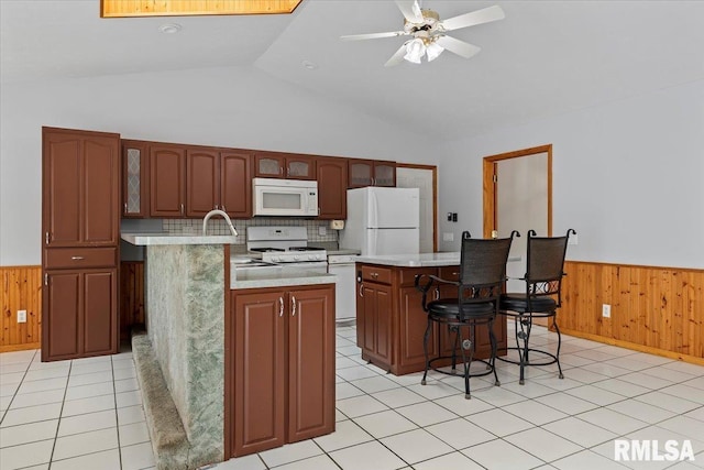 kitchen with white appliances, light countertops, wainscoting, and a center island