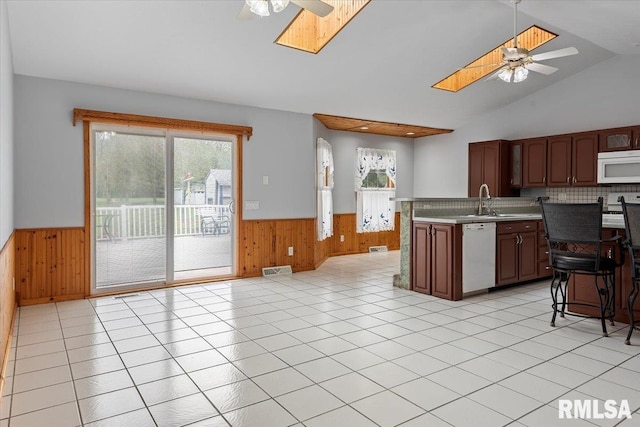 kitchen featuring white appliances, a ceiling fan, wood walls, and wainscoting