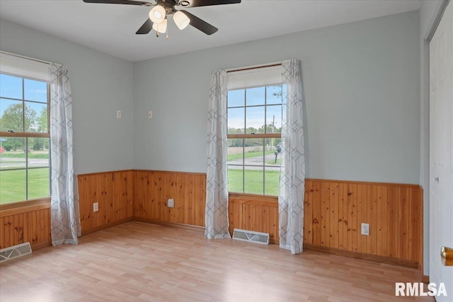 unfurnished room featuring wood finished floors, a wainscoted wall, and a wealth of natural light