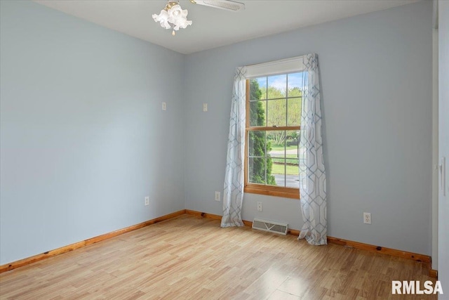 empty room with baseboards, visible vents, and wood finished floors