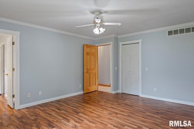 unfurnished bedroom featuring baseboards, wood finished floors, and visible vents
