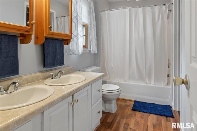 full bath with double vanity, a sink, wood finished floors, and toilet