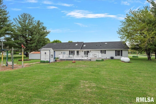 rear view of property with a storage unit, a yard, an outbuilding, and a deck