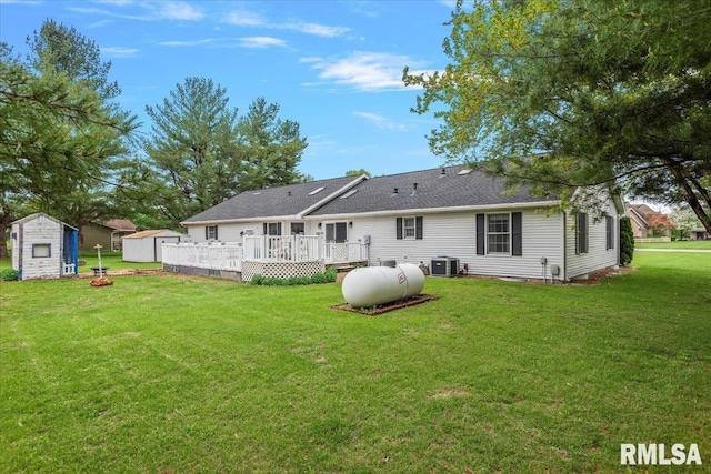 back of property featuring central AC, a deck, a storage unit, a lawn, and an outbuilding