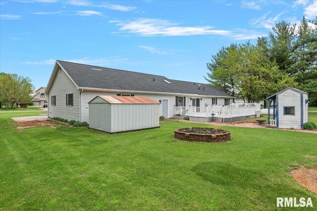 back of house featuring a storage unit, an outbuilding, a yard, and an outdoor fire pit