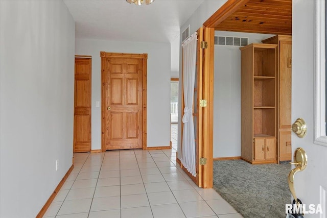 hallway featuring baseboards, light tile patterned flooring, and visible vents