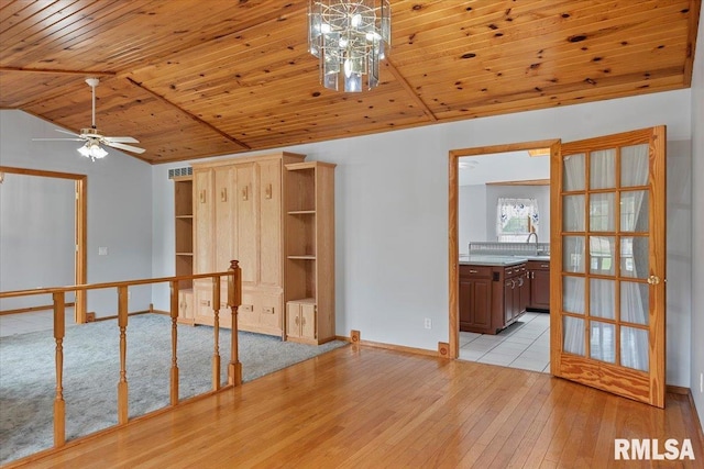 interior space featuring ceiling fan with notable chandelier, baseboards, lofted ceiling, light wood-type flooring, and wood ceiling