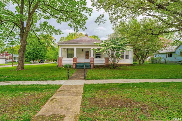 view of front of home featuring a porch, a front lawn, and a chimney