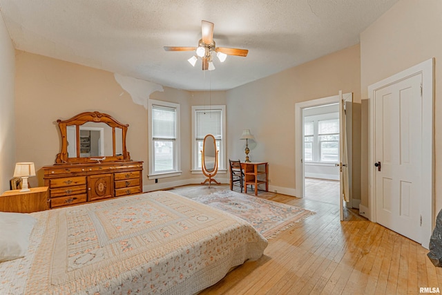 bedroom with a textured ceiling, baseboards, a ceiling fan, and light wood-type flooring