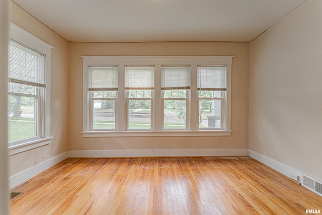 spare room featuring light wood-type flooring, baseboards, and visible vents
