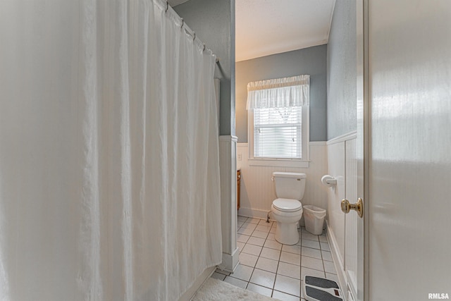 bathroom featuring tile patterned floors, wainscoting, and toilet