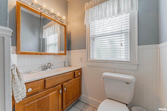 bathroom with vanity, tile patterned floors, wainscoting, and toilet
