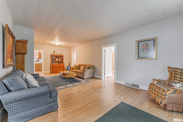 living room with baseboards, visible vents, and hardwood / wood-style floors
