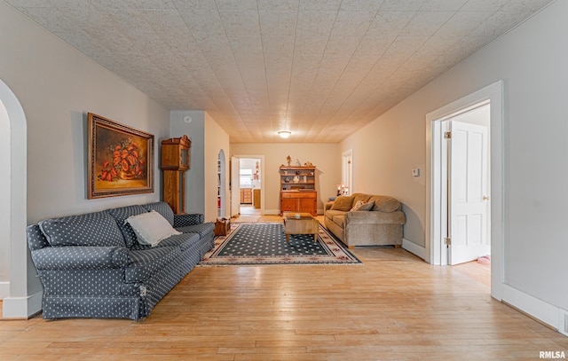 living area with arched walkways and light wood-type flooring