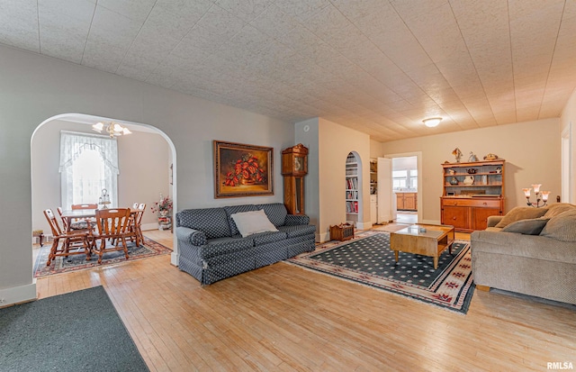 living area featuring arched walkways, hardwood / wood-style floors, and a chandelier