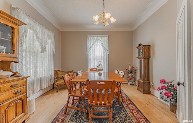 dining room with ornamental molding, light wood-type flooring, and a chandelier