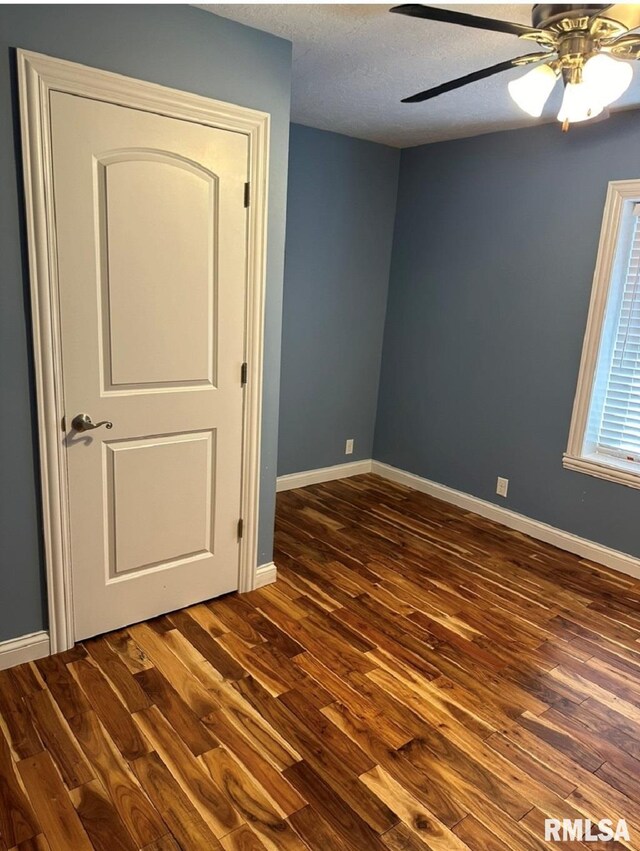 unfurnished room with baseboards, ceiling fan, dark wood finished floors, and a textured ceiling