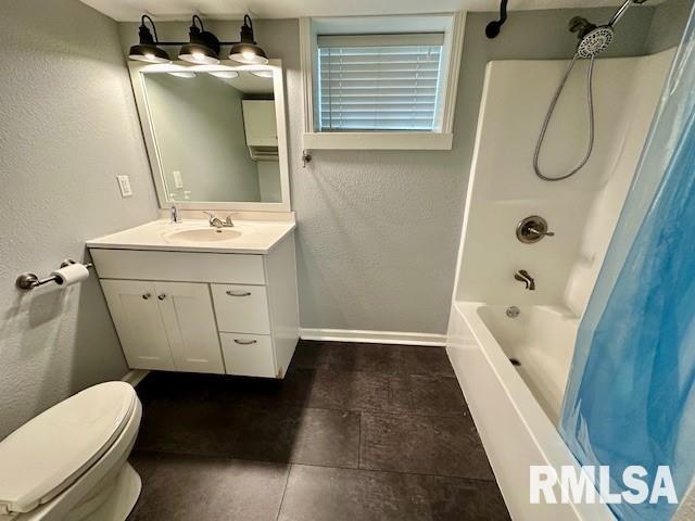 bathroom with vanity, a textured wall, toilet, baseboards, and shower / tub combo