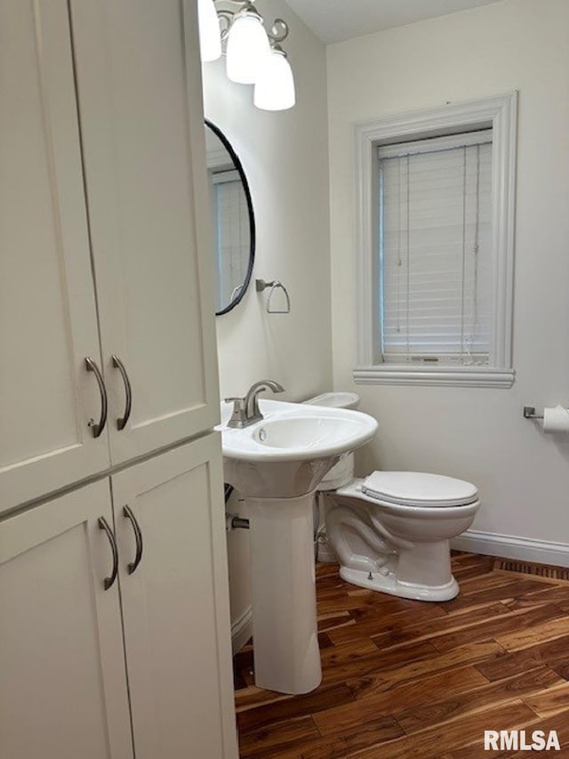 bathroom with baseboards, wood finished floors, and toilet