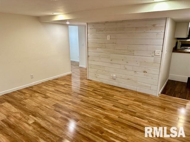 spare room with baseboards and wood finished floors