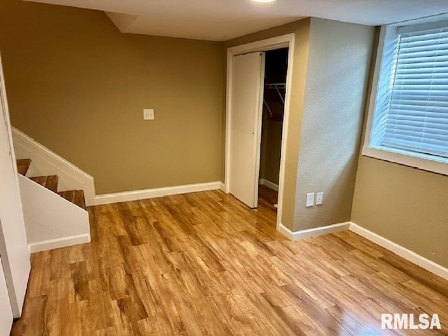 unfurnished bedroom featuring baseboards, wood finished floors, and a closet