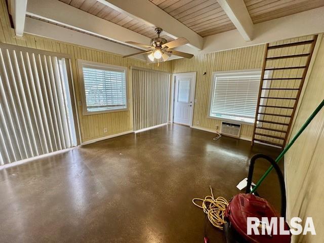 spare room with a ceiling fan, a wall mounted AC, beam ceiling, and finished concrete flooring