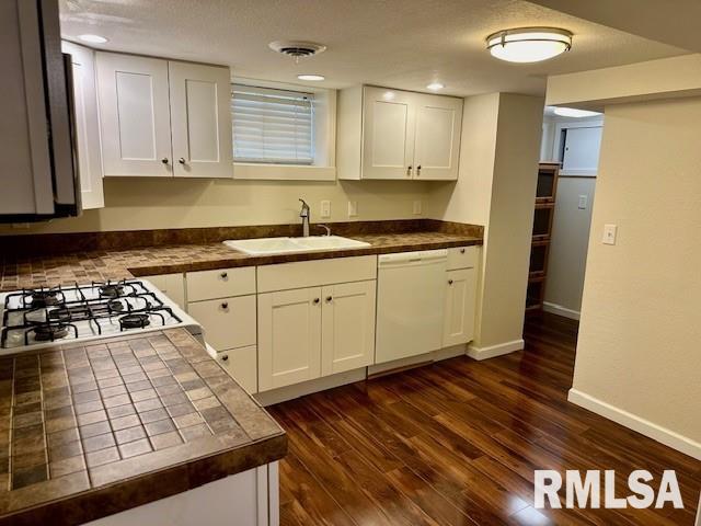 kitchen with tile countertops, white cabinetry, a sink, and dishwasher