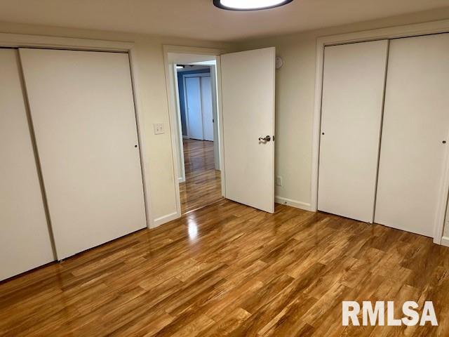 unfurnished bedroom featuring two closets and wood finished floors