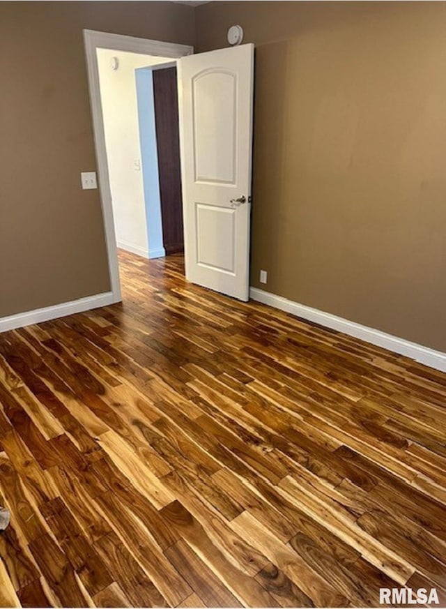 unfurnished room featuring baseboards and dark wood finished floors
