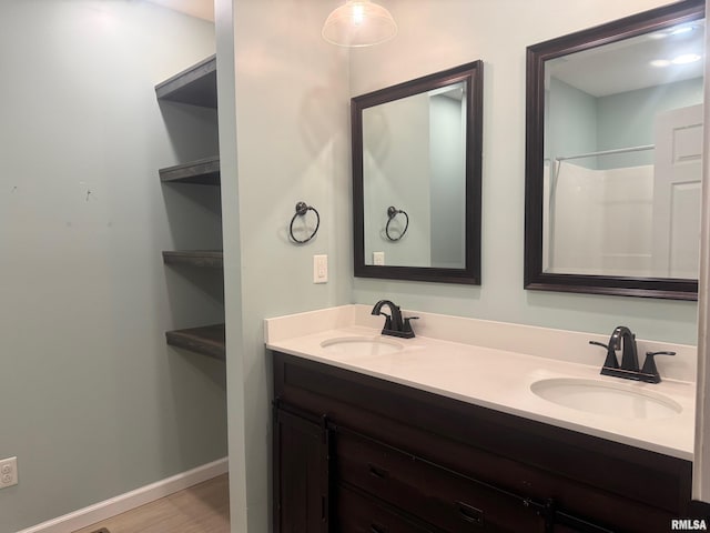 912 N Main St, Monroe City, MO 63456 - bathroom with double vanity, baseboards, a sink, and wood finished floors