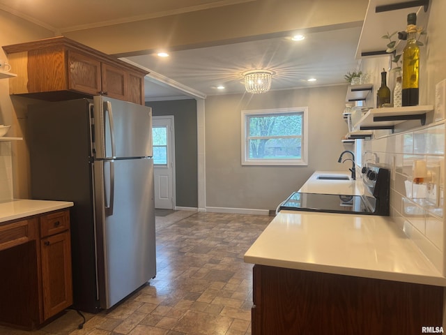 912 N Main St, Monroe City, MO 63456 - kitchen with crown molding, brown cabinets, a sink, freestanding refrigerator, and stone tile flooring
