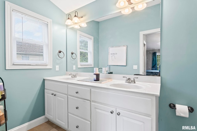bathroom featuring healthy amount of natural light, tile patterned flooring, double vanity, and baseboards