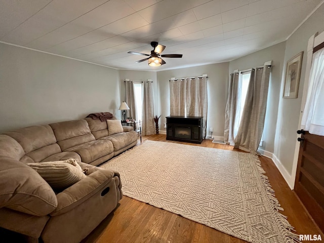 living room featuring ornamental molding, ceiling fan, wood finished floors, and a fireplace
