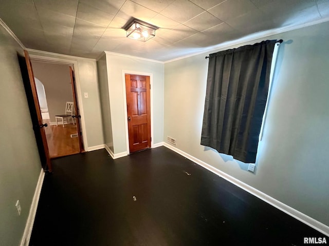spare room featuring crown molding, baseboards, and visible vents