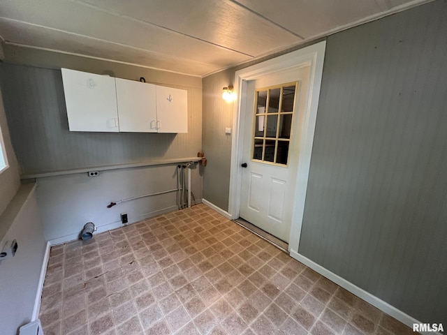 washroom featuring hookup for a gas dryer, cabinet space, baseboards, wooden walls, and light floors