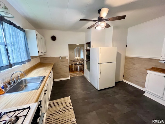 kitchen featuring a ceiling fan, white appliances, wooden counters, white cabinetry, and a sink